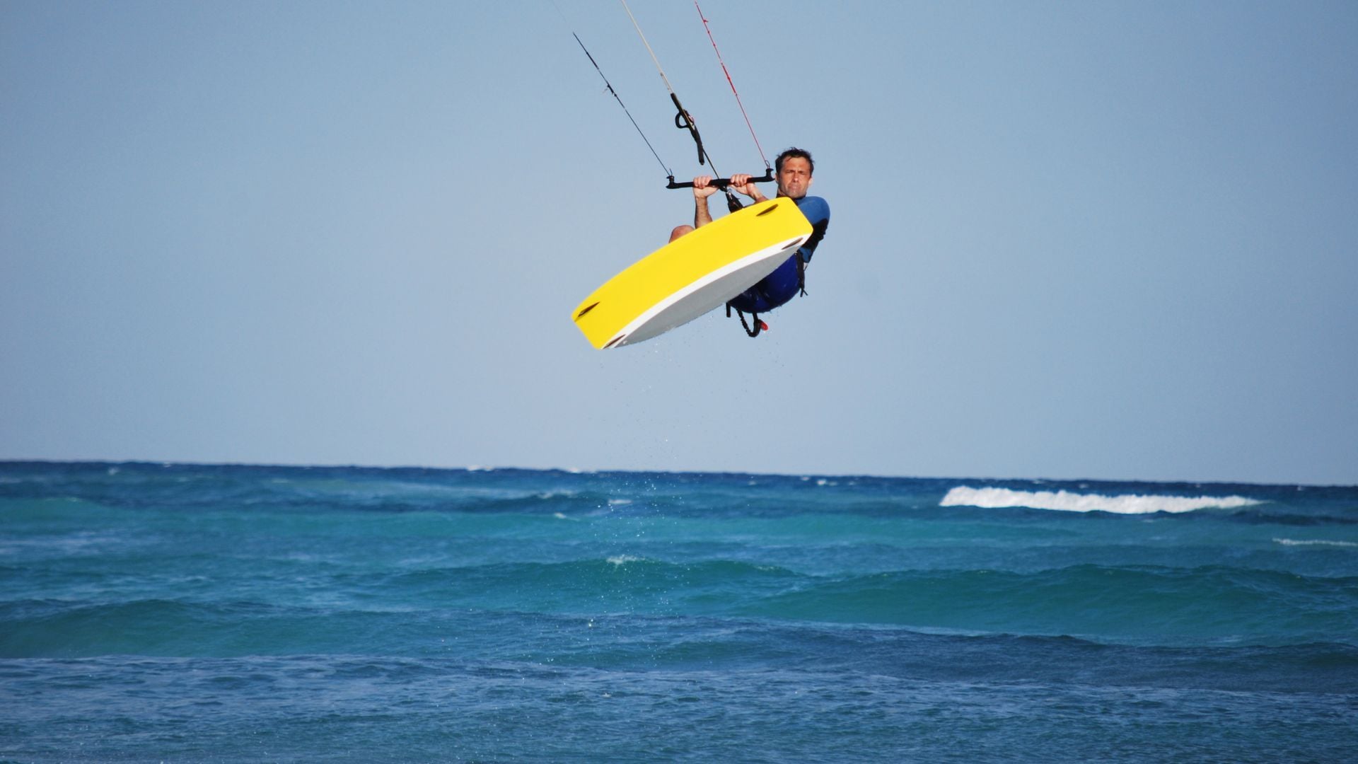 A kitesurfer powered up on a windy, sunlit beach in Tarifa.