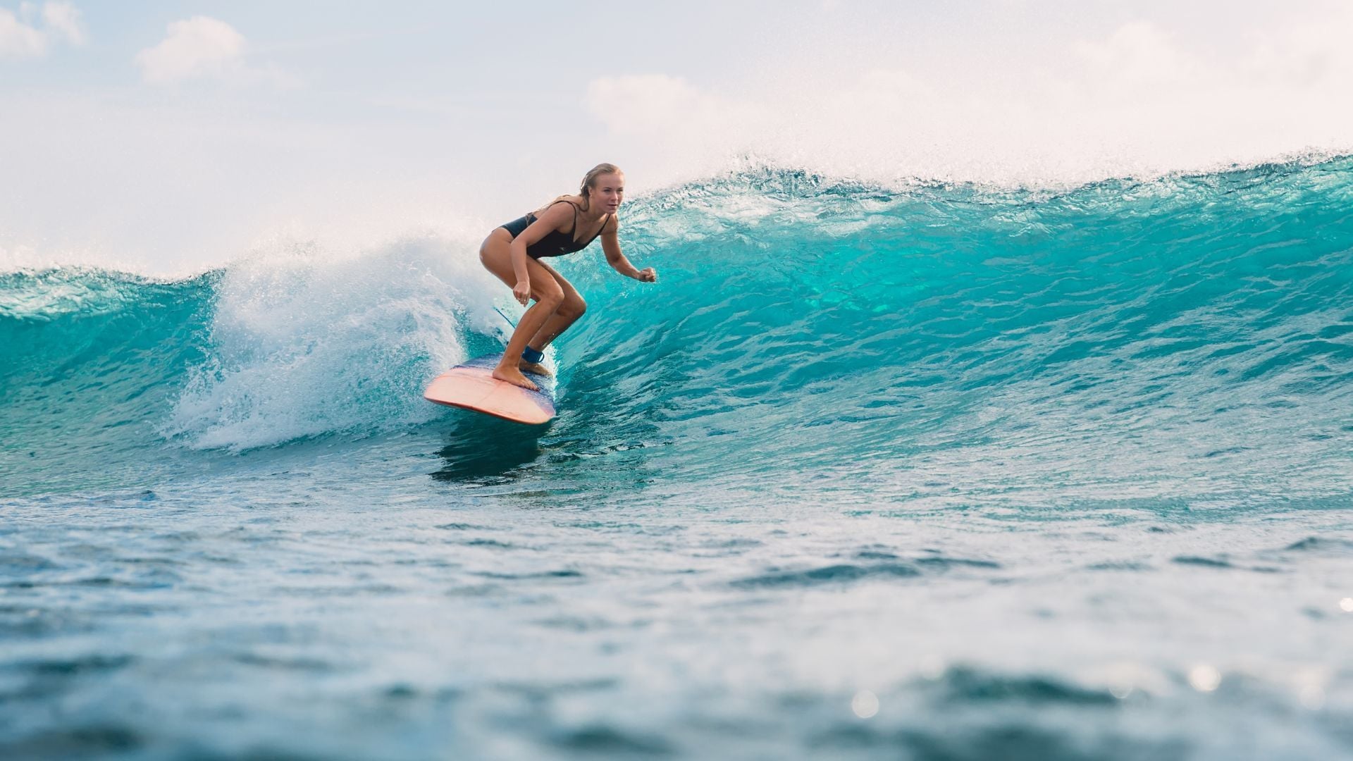 A surfer checking conditions from a headland above a clean beach break.